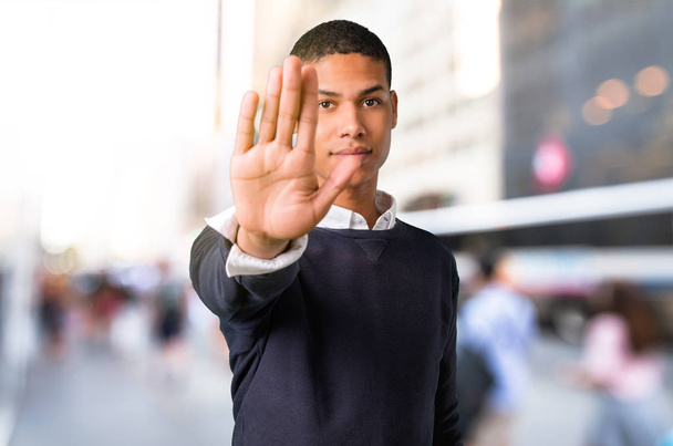 Jeune homme afro-américain faisant un geste d'arrêt avec sa main au milieu de la ville
 - Photo, image