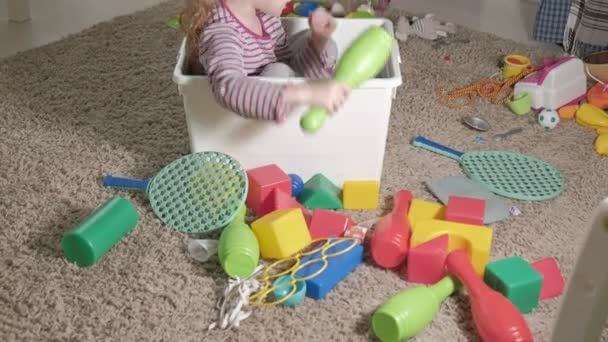 Beau petit enfant riant, blonde préscolaire, jouant avec des jouets colorés dans une boîte blanche, assis sur le sol dans la chambre
 - Séquence, vidéo