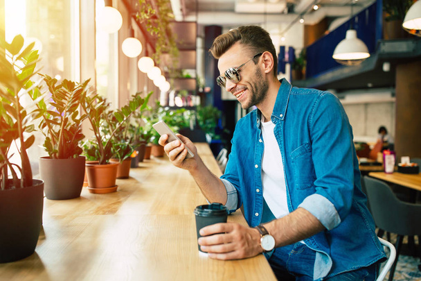 fiatal ember használ smartphone kávézóban ülve - Fotó, kép