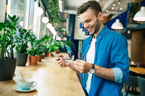 young man with credit card and smartphone at cafe, online shopping concept - Photo, image