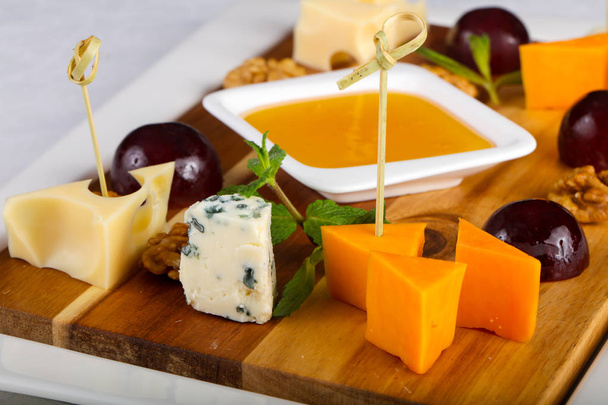 Assiette de fromage mélange avec raisin, miel et noix
 - Photo, image