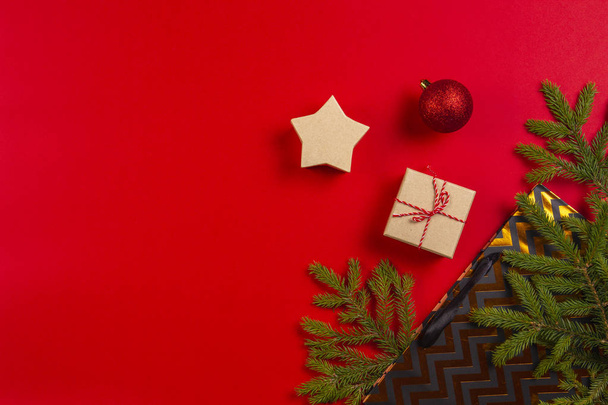 Kerst samenstelling. Spar boomtakken, kerstversiering en huidige tas, de doos van de gift op rode achtergrond - Foto, afbeelding