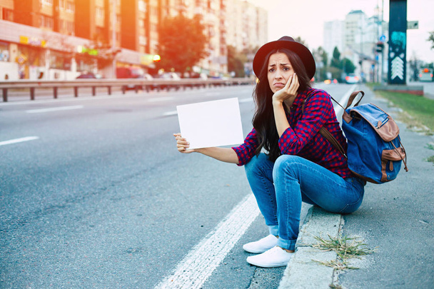 Disappointed and tired woman trying to hitch-hiking car in city - Foto, afbeelding