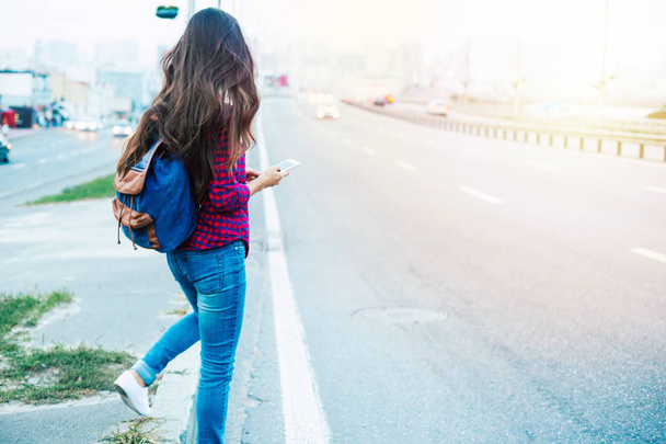 Young casual woman using smartphone on urban road-side - Zdjęcie, obraz