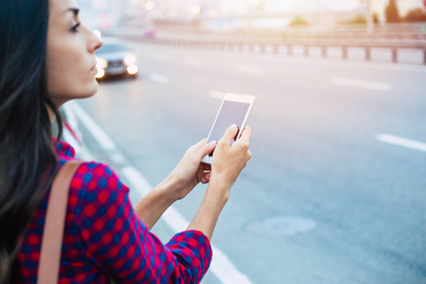 Young casual woman using smartphone on urban road-side - Foto, Imagem