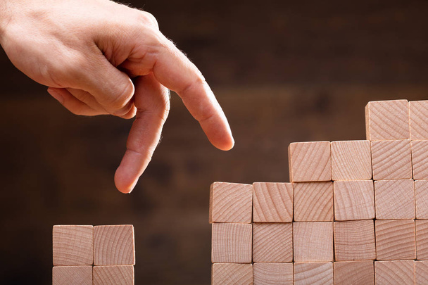 Close-up Of A Person Stepping Finger On Stacked Wooden Blocks - Photo, image