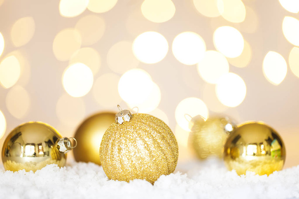 Golden Christmas baubles on snow, tree lights background - Foto, immagini