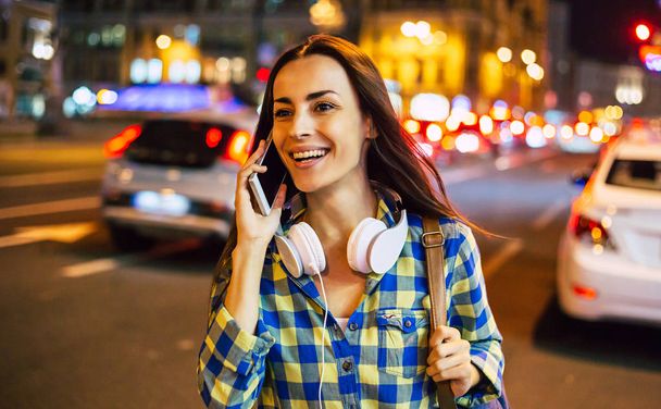 Young smiling woman using smartphone on bright city street - Fotó, kép