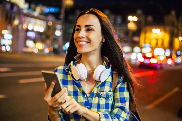 Young smiling woman using smartphone on bright city street - Foto, Imagem