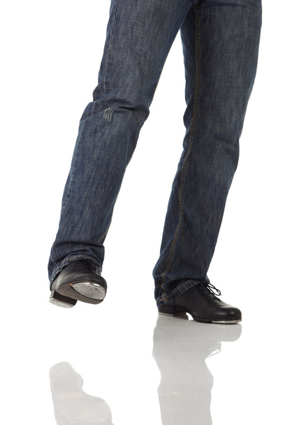Single male tap dancer wearing jeans showing various steps in studio with white background and reflective floor. - Foto, Bild