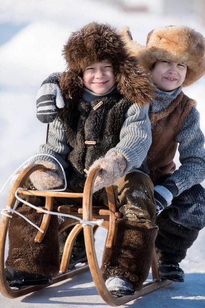 Two boys sledding with mountain warm winter day - Fotografie, Obrázek