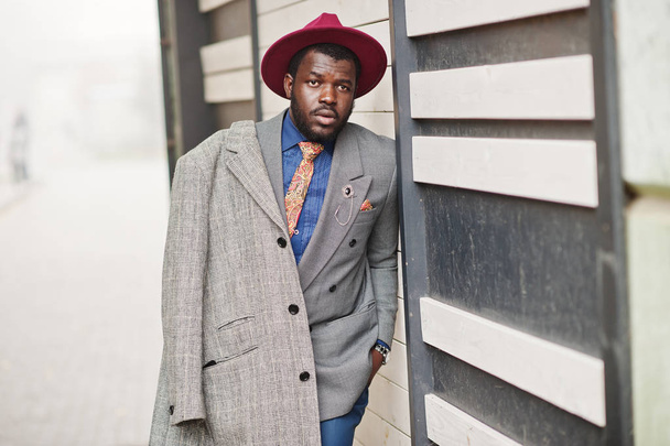 Stylish African American man model in gray coat, jacket tie and red hat.  - 写真・画像
