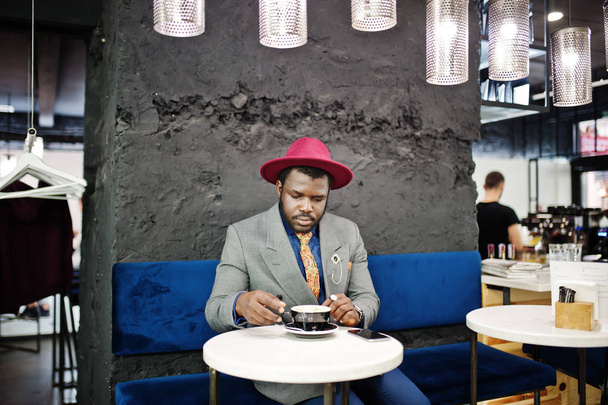 Stylish African American man model in gray jacket tie and red hat drink coffee at cafe. - Φωτογραφία, εικόνα