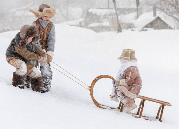 Three children sledding with mountain warm winter day - Фото, зображення