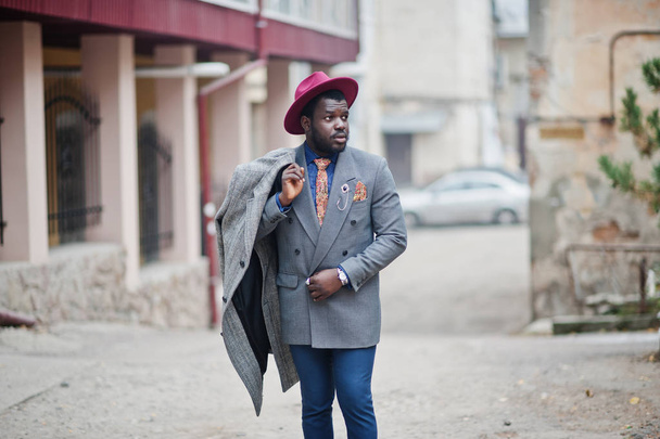 Stylish African American man model in gray coat, jacket tie and red hat.  - 写真・画像