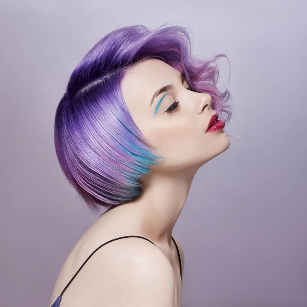 Portrait of a woman with bright colored flying hair, all shades of purple. Hair coloring, beautiful lips and makeup. Hair fluttering in the wind. Sexy girl with short  hair. Professional coloring - Фото, зображення