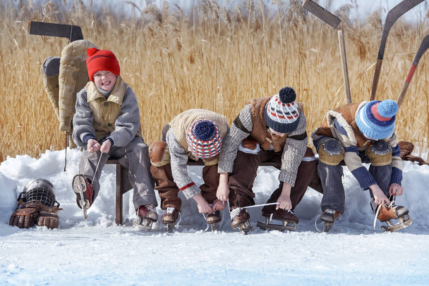 Gruppe von Jungen wird auf einer Bank am örtlichen See gegen Hockey getauscht - Foto, Bild