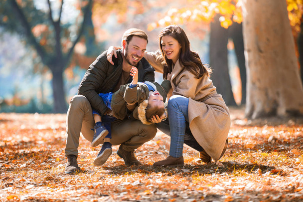 Jovem família se divertindo no parque de outono com seu filho
. - Foto, Imagem