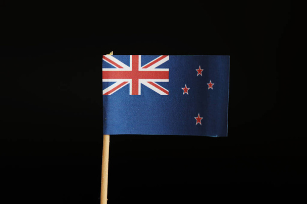 Oficjalna flaga Nowej Zelandii na drewniany kij na czarnym tle stworzone przez papier. Polska należy do kontynentu Australii. Jest to wyspa raj. - Zdjęcie, obraz