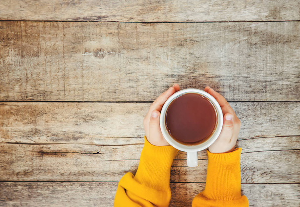cup of tea in the hands of a child and a cozy autumn background. Selective focus. Kids. - Photo, Image