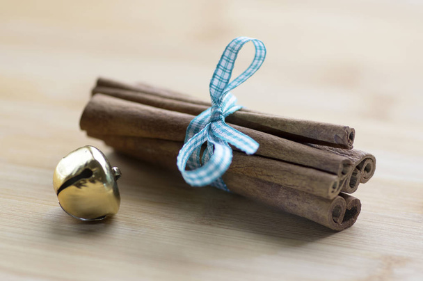 Group of cinnamon tied with checkered light blue bow, golden jingle bell - Fotó, kép