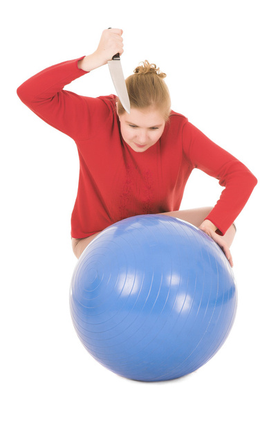 Frustrated blonde middle aged woman with a large carving knife about to kill a yoga ball - Foto, imagen
