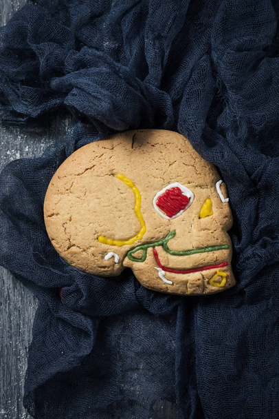 high angle view of a homemade skull-shaped cookie for Hallowen, on a gray rustic wooden table - Fotoğraf, Görsel