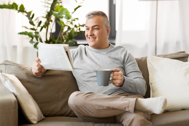 man reading newspaper and drinking coffee at home - Valokuva, kuva