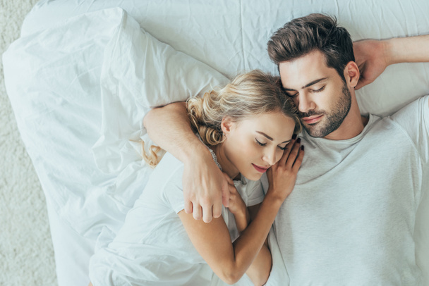 top view of beautiful young couple sleeping together and hugging in bed at home - Photo, Image