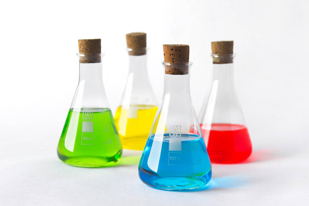 Four laboratory flasks with cork plugs and colorful liquids isolated on white. - Foto, Imagen