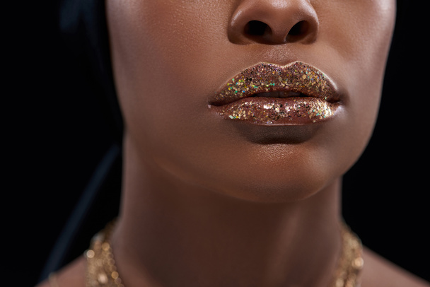 tiro recortado de mujer afroamericana con brillo labial brillante aislado en negro
 - Foto, Imagen