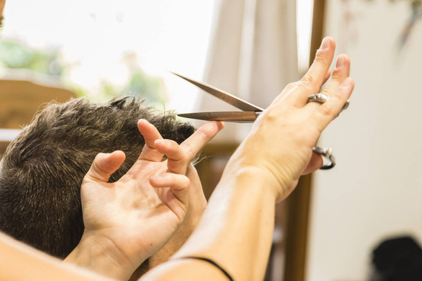 Duas mãos cortando o cabelo de um homem
 - Foto, Imagem