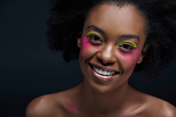 明るいネオン化粧ポーズ ブラックに分離された陽気なアフリカ系アメリカ人モデルの肖像 - 写真・画像