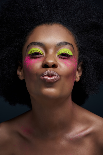portrait of african american model with bright neon makeup and duck face posing isolated on black - Foto, Imagem