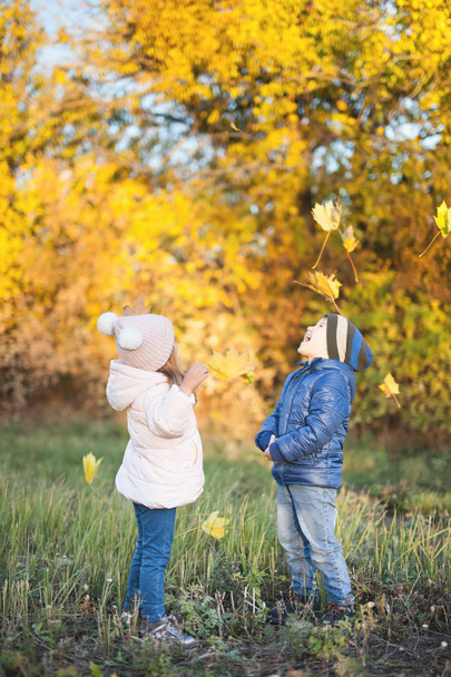 Happy kids walking outdoor at autumn park throw leaves - Foto, Bild