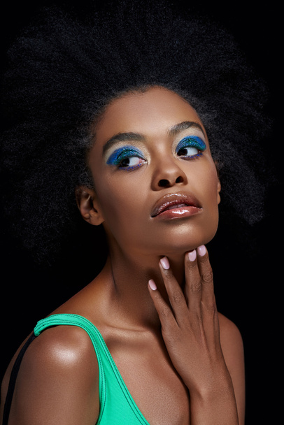 portrait of pensive african american model with bright blue eyes shadows isolated on black - Photo, Image