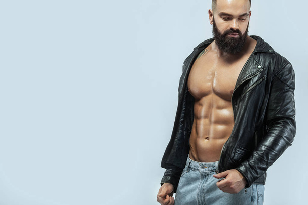 Close-up portrait of a brutal bearded man topless in a leather jacket - Foto, imagen
