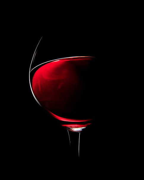 Jedna sklenice červené víno fotografoval s osvětlili proti černému pozadí (zaměření na okraji skla) - Fotografie, Obrázek