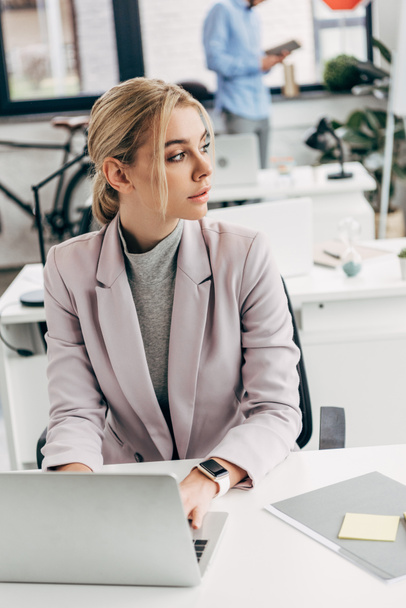 young businesswoman looking away while working with laptop in office  - Photo, Image