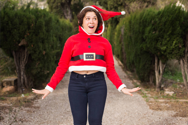 Christmas, holidays, humor and people concept - funny happy woman in santa suit dancing outdoors - Photo, Image