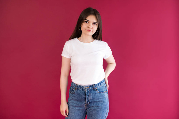 Beautiful girl in a white t-shirt on a red background. Mock-up. - Foto, afbeelding