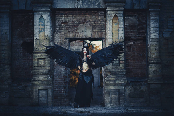 hübsches Dämonenmädchen mit schwarzen Flügeln hinter ihrem Rücken, Göttin einer anderen Welt jenseits, schwarzer Engel zu Halloween. - Foto, Bild