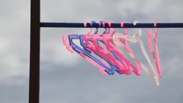 rosa und violette Kleiderbügel am Stand vor bewölktem Himmel - Filmmaterial, Video