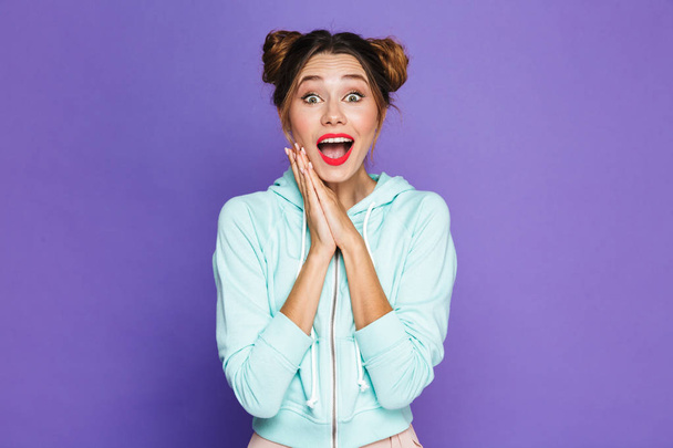 Image of excited woman with two buns laughing and keeping hands together isolated over violet background in studio - Foto, immagini
