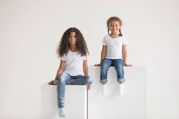 Cute little african american girls in white t-shirts. Mock-up. - 写真・画像