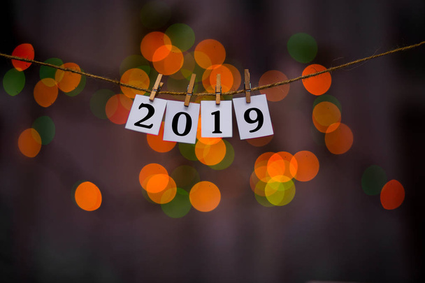 Happy new year 2019 text on papers with clothespins with garland bokeh on background. Year of pig - Φωτογραφία, εικόνα