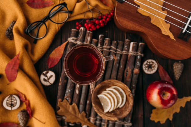 Flat lay. Textured scarf with cup of tea . Autumn leaves on wooden background . Autumn or Winter concept. - Zdjęcie, obraz