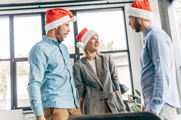 young start up team in santa hats looking at each other in office - Φωτογραφία, εικόνα