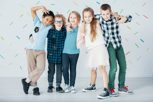 Multicultural group of children against colorful wallpaper. Young friends in the school - Fotografie, Obrázek