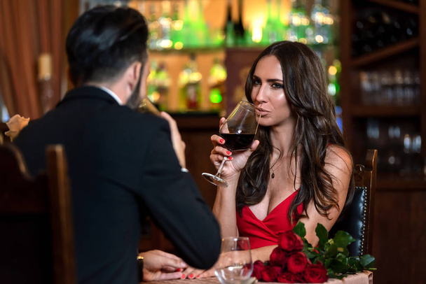 Attractive couple in love is dating and drinking wine during romantic dinner in the restaurant. - Photo, Image